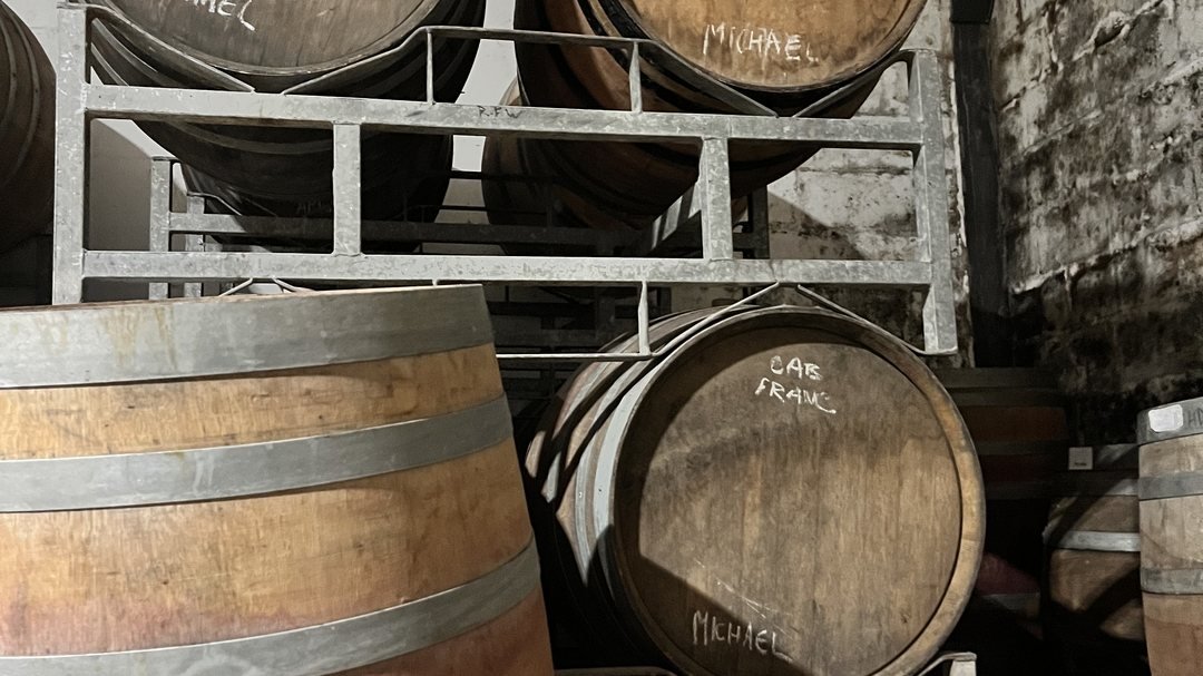 Oak barrels in a cellar, chalked with the names Michael and Cab Franc